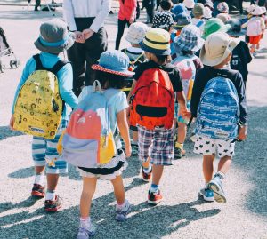 Four elementary students with backpacks walking